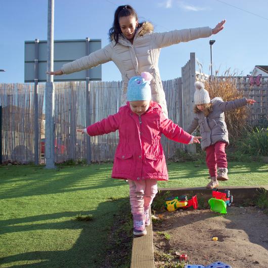 Child and teacher walk across obstacle course