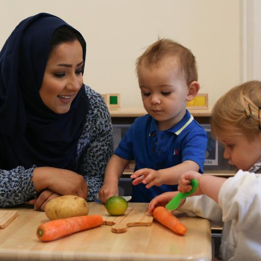 children practicing some cutting with vegetables in the home corner