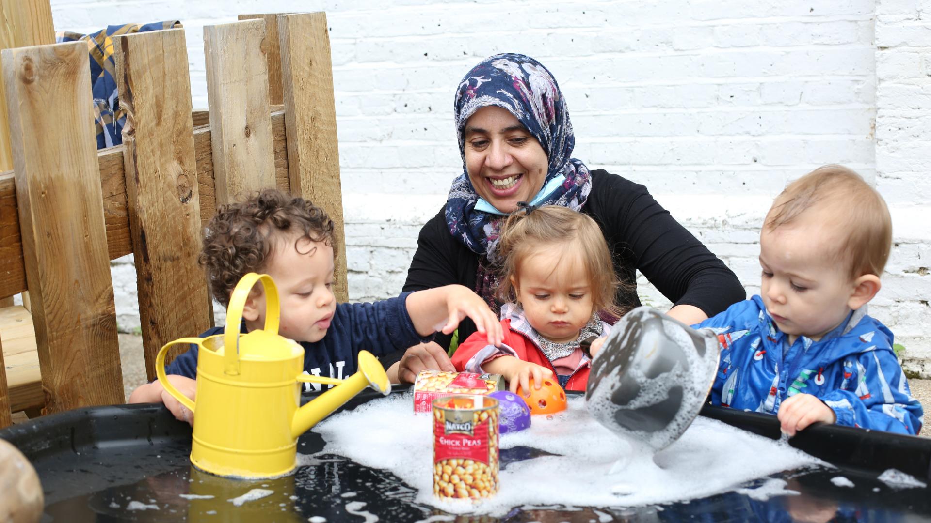 Staff and children enjoying water play outside in the garden