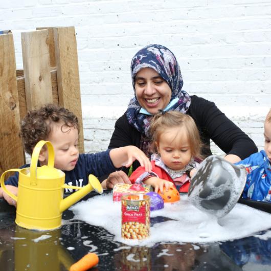 Staff and children enjoying water play outside in the garden