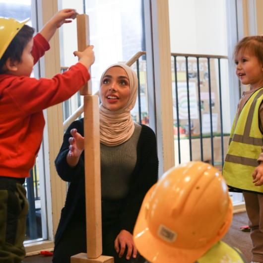 Staff and children building a high tower using building blocks