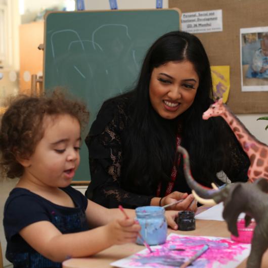 Child painting animals with staff
