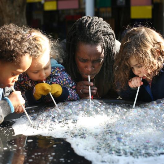 staff and children making bubbles outside