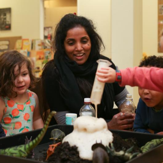 staff and children together doing a science experiment watching a volcano erupt