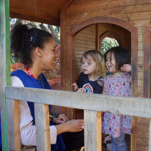 Staff and children playing outside in the garden wooden house