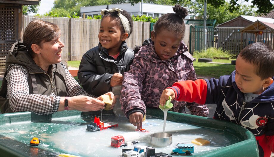 Children and staff washing toy cars outside
