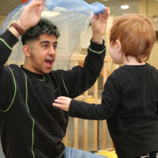 Male staff throwing a mesh material over child's head