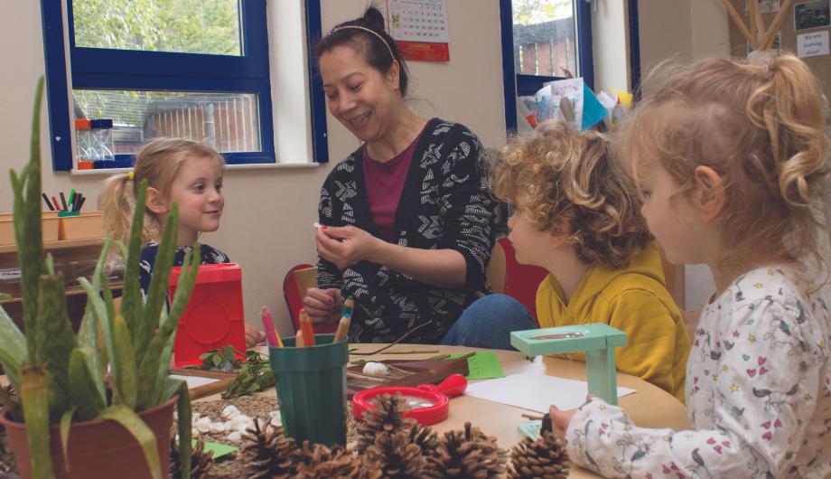 staff and children looking at different natural materials, such as shells and pine cones.