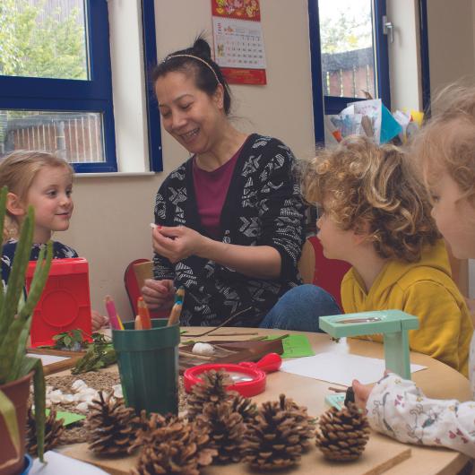 staff and children looking at different natural materials, such as shells and pine cones.