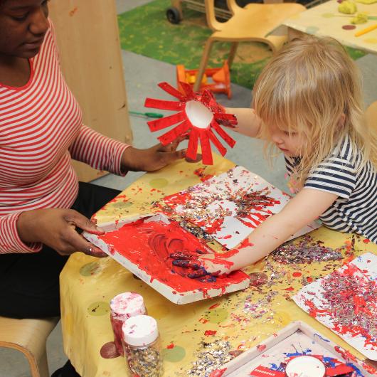 child and staff creating glittery fireworks and getting messy