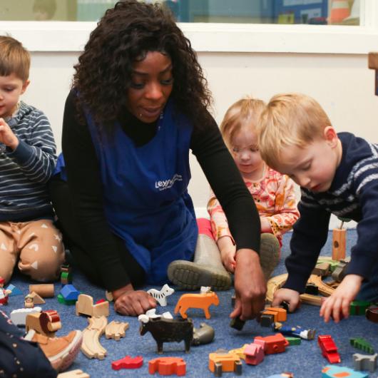 Staff and a group of children setting up a small world with small animals and people