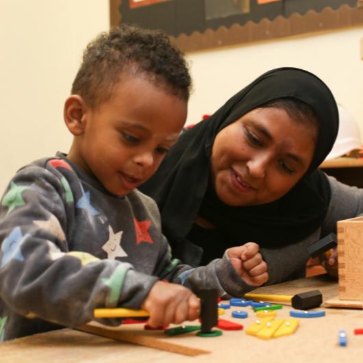 Staff watching child as he hammers in some small nails