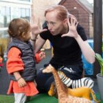 Staff and child playing with safari animal toys