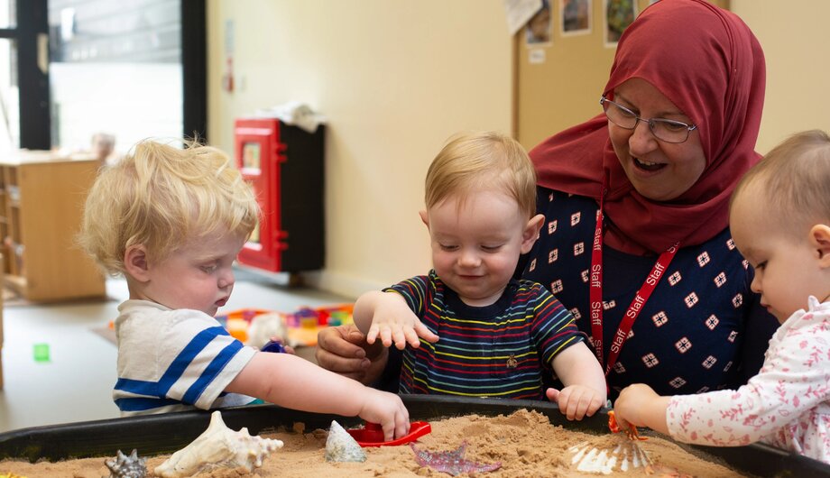 Teacher and children playing with sea animals in the sand