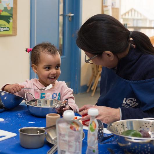 staff and child using fruits and vegetables to cook or bake something