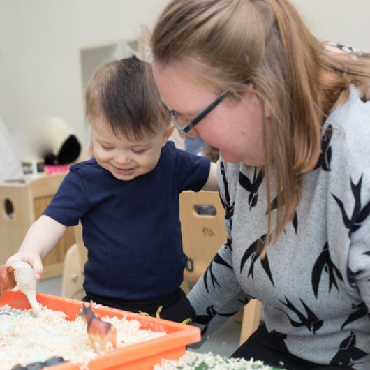 staff and child playing very closely with the small plastic animals