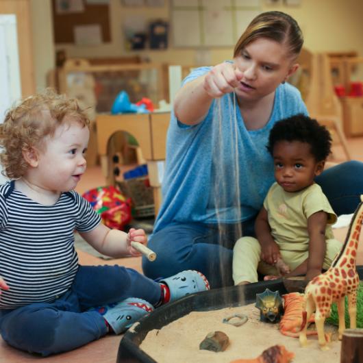 staff and children playing some plastic animals and sand