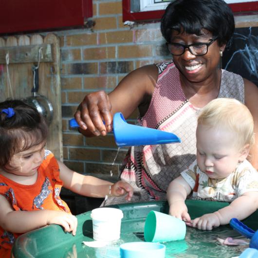 Staff and children playing with water outside in the garden