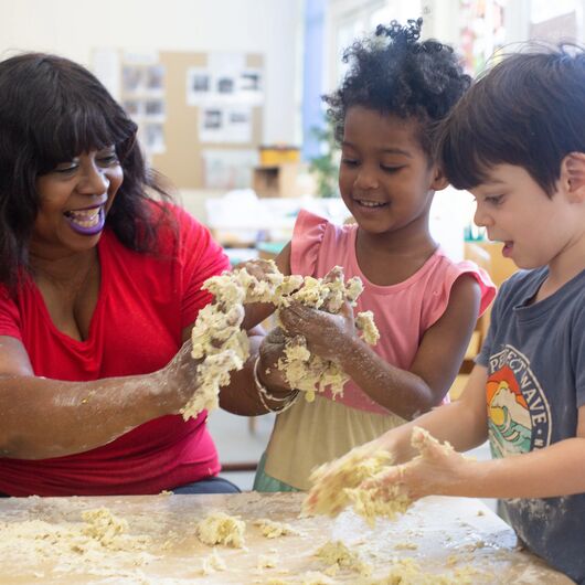 teacher and pre-school children making dough.