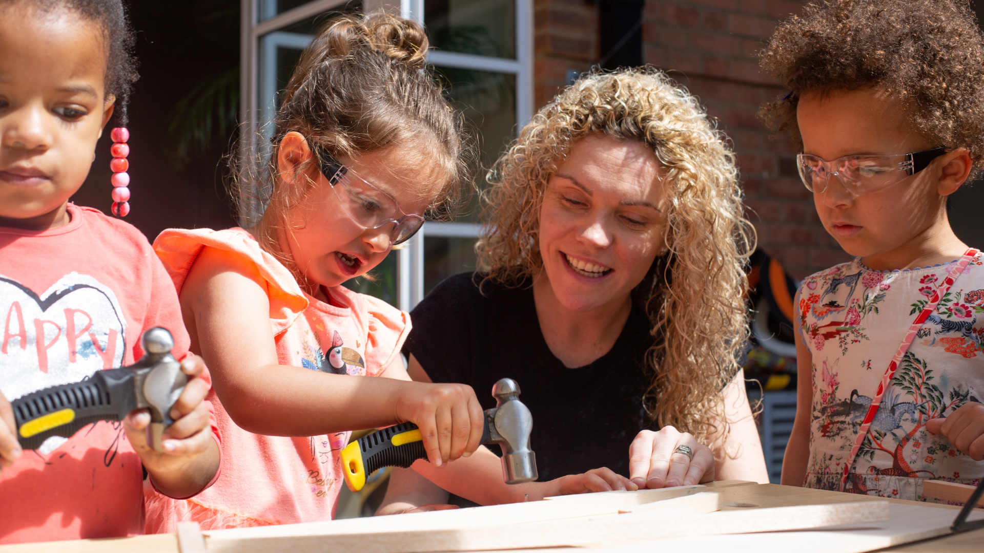 Nursery Manager helping a child use a hammer and nail