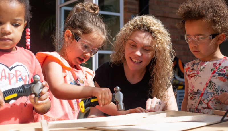 Nursery Manager helping a child use a hammer and nail