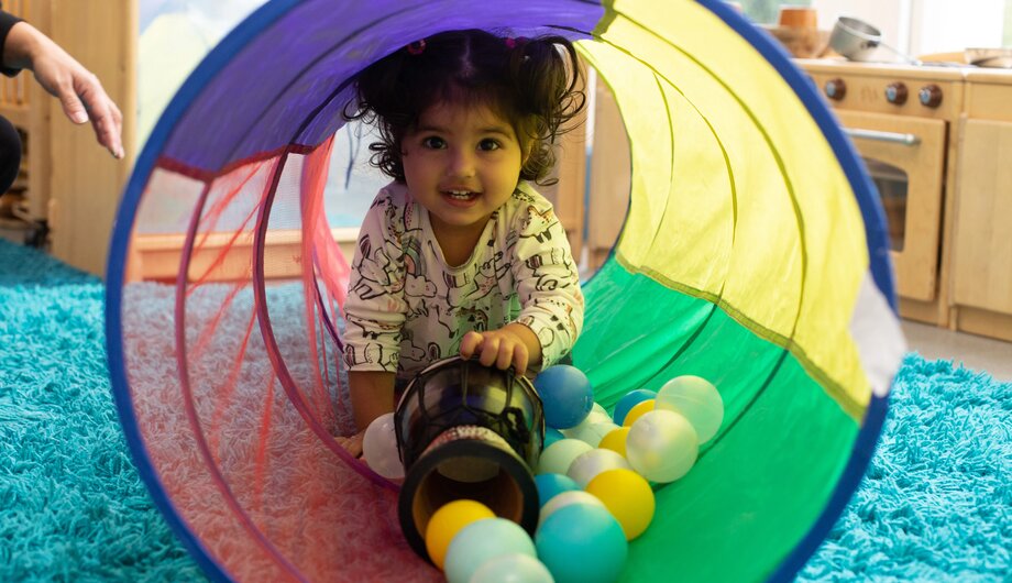 Child going through tunnel with balls