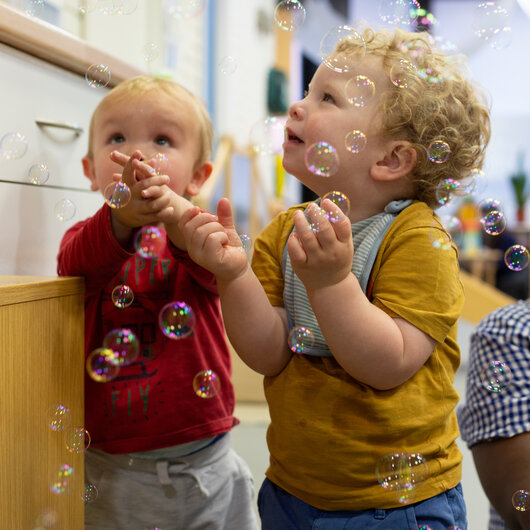 Children looking and trying to catch bubbles