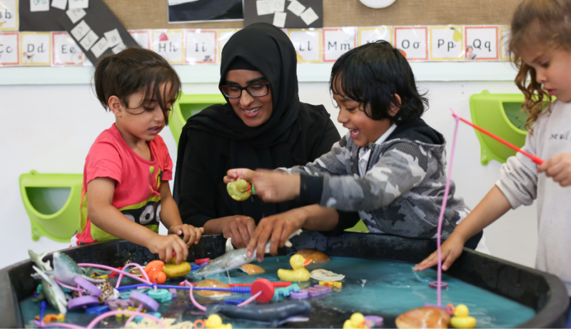 staff and children enjoying some wet play with fish nets and sea animals