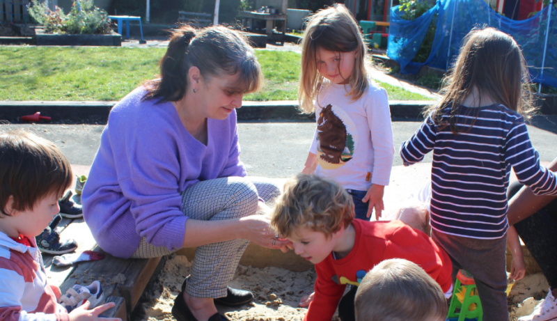 Staff playing in the sand outside with the children in the garden