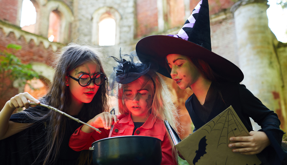 children dressed up as witches by a saucepan