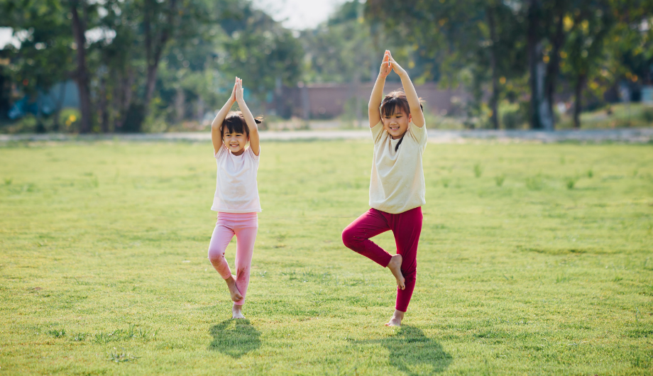 two children doing yoga outdoors