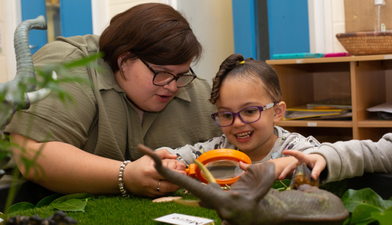 Staff and child looking through a magnifying glass