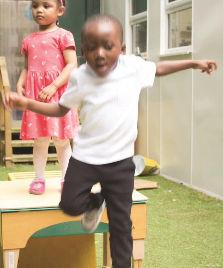 Child jumping from an outdoor obstacle course platform