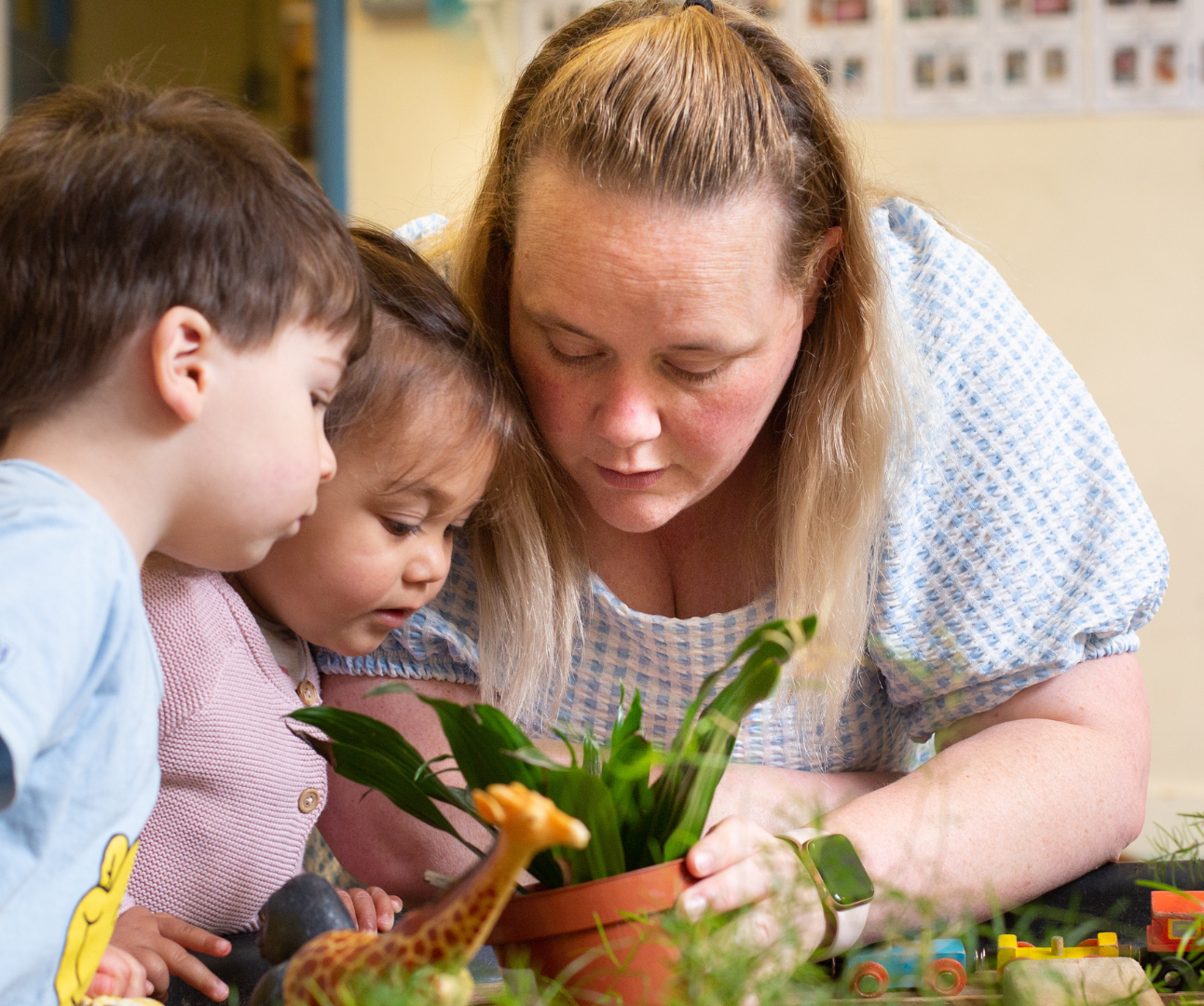 staff and children looking very curiously into a plant pot