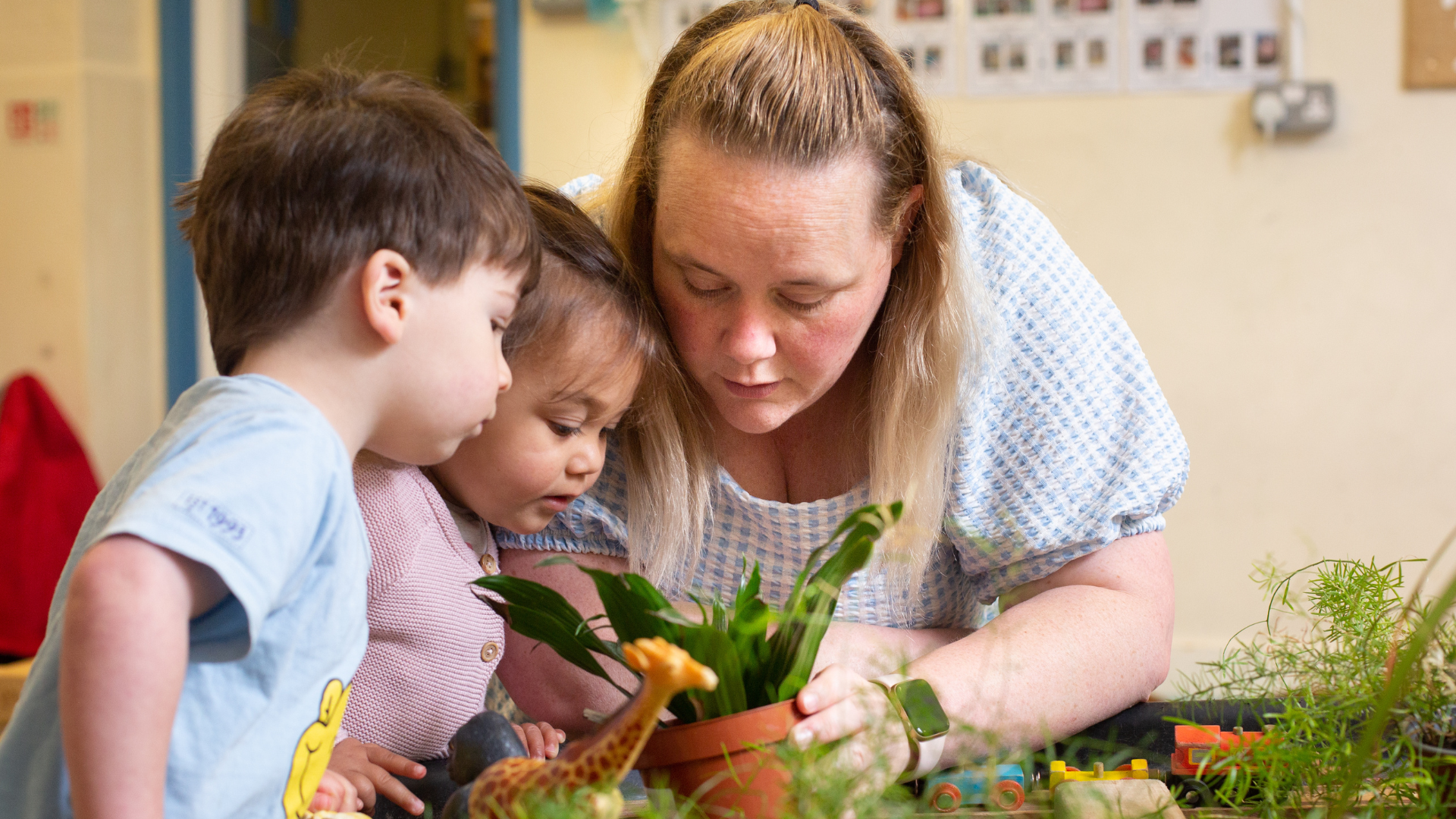 staff and children looking very curiously into a plant pot