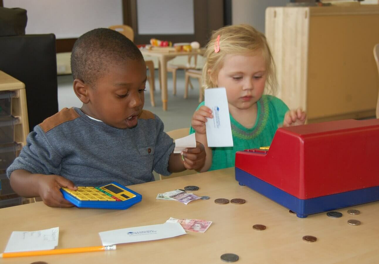 Two children with a calculator, coins and a play till