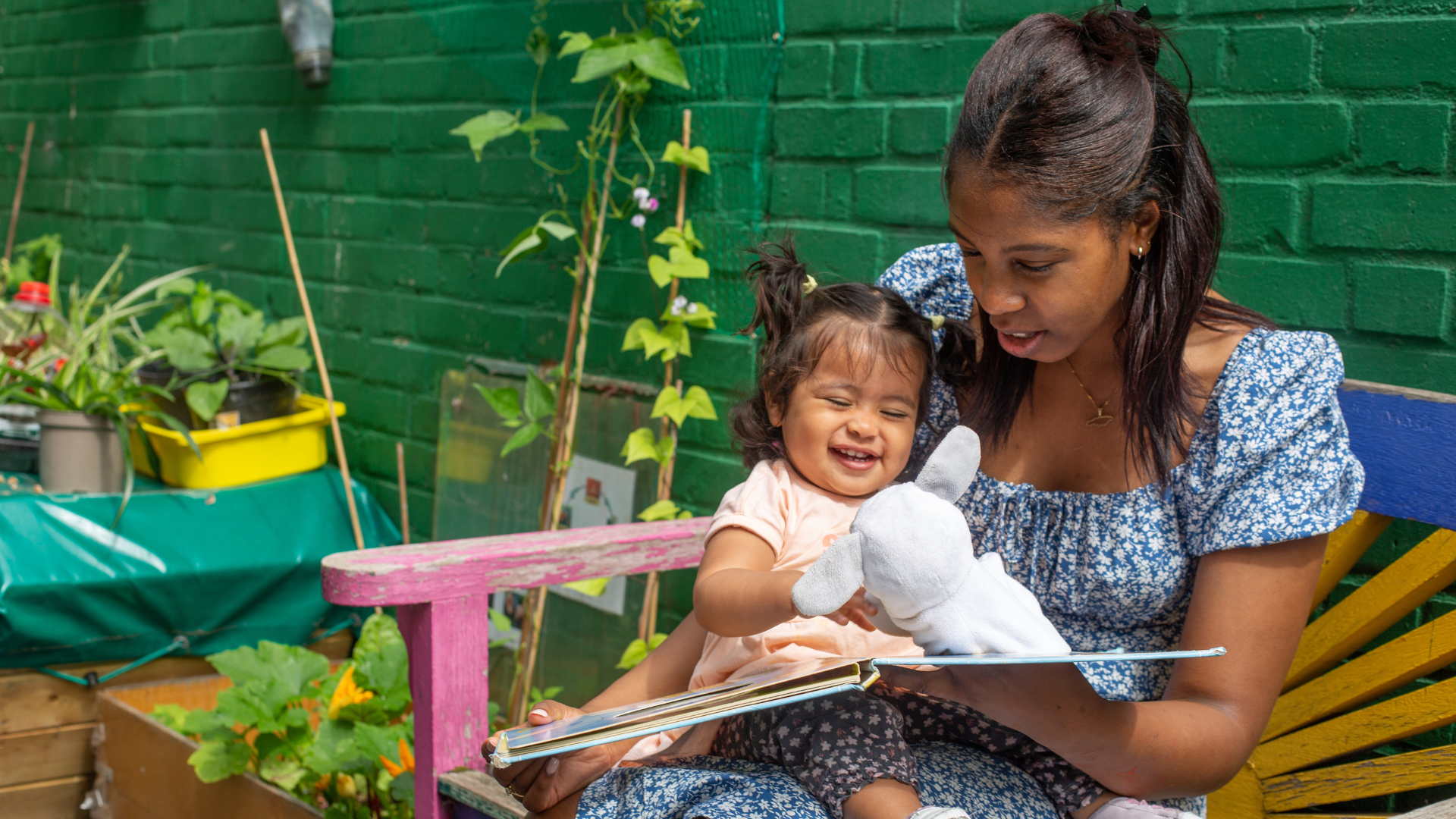 staff and child sitting outside in the garden reading
