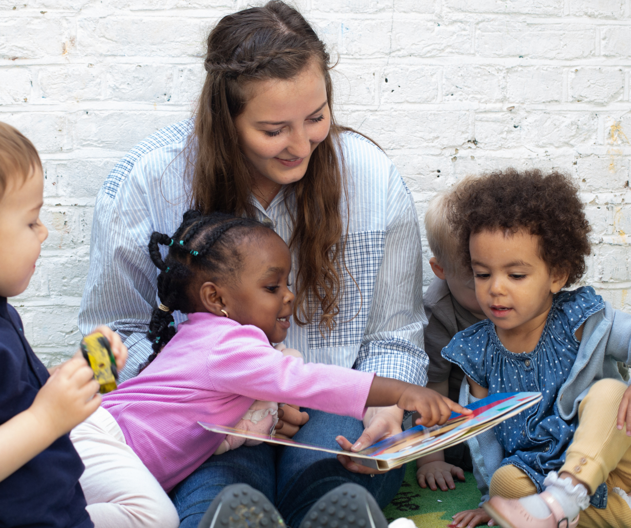 staff and children sitting outside in the garden reading