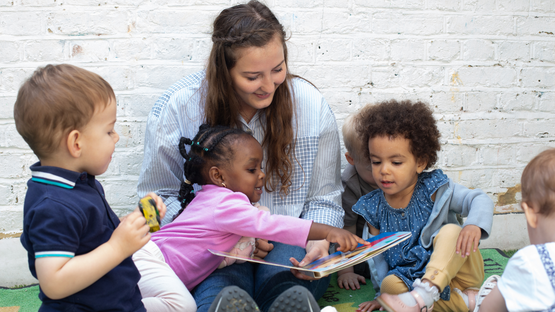 staff and children sitting outside in the garden reading