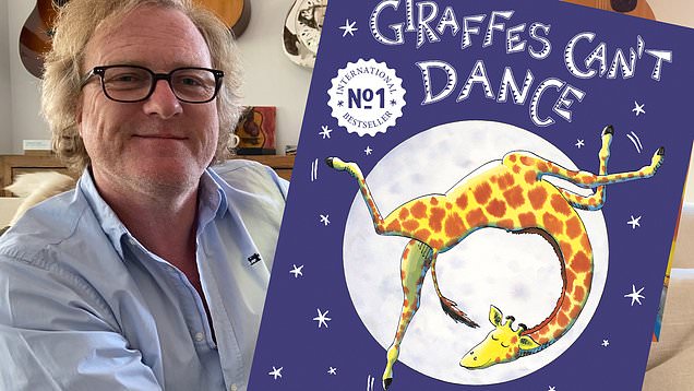 Giles Andreae holding the book Giraffe's Can't Dance