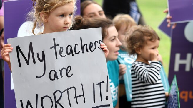 Little girl holding a banner saying My teachers are worth it!