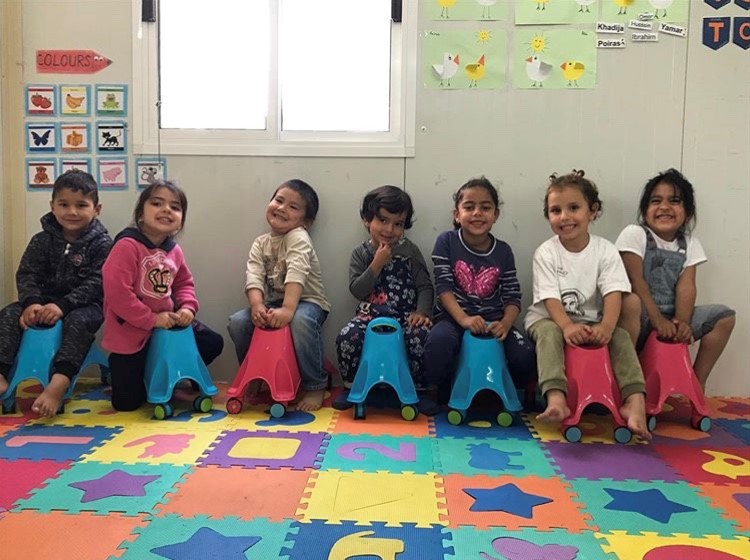 A group of children sitting on wheeled ride on toys