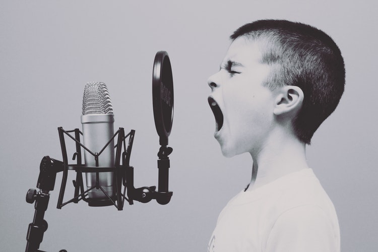 Black and white photo of a boy shouting into a microphone