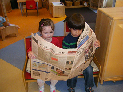 Two children sitting reading the Financial Times together