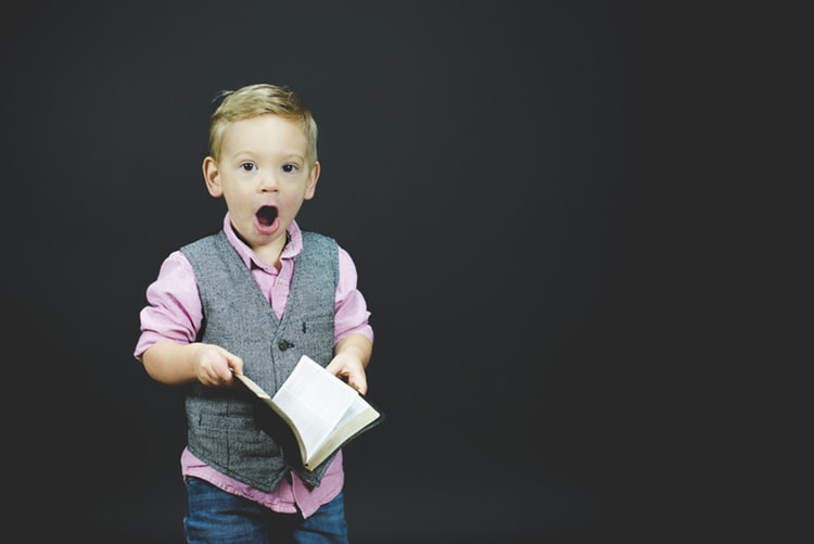 Image of a small boy looking amazed at something he has read in a reference book