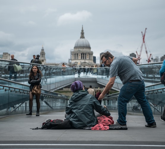 Photo of a homeless person being given change by a man