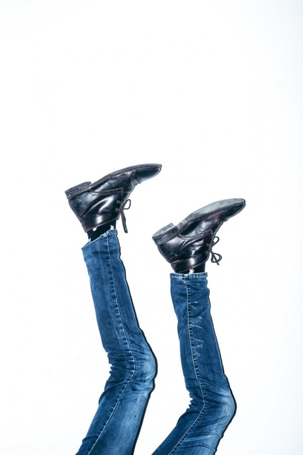 A pair of legs, wearing jeans and boots, sticking up in the air