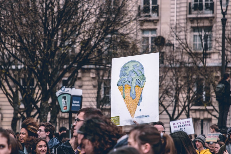 A placard being held at a demonstration depicting the world as an ice cream melting on a cone