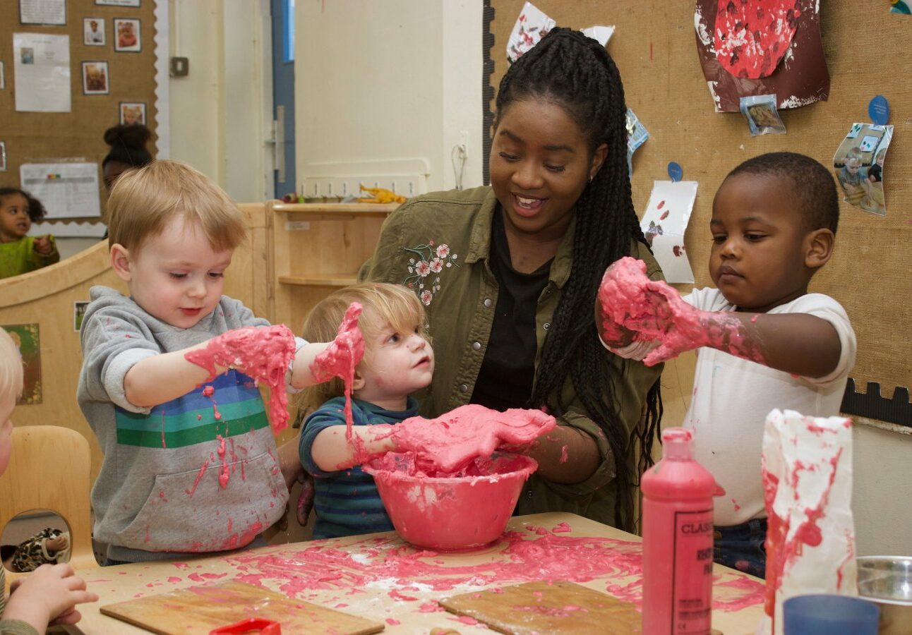 Teacher with three children playing with pink slime