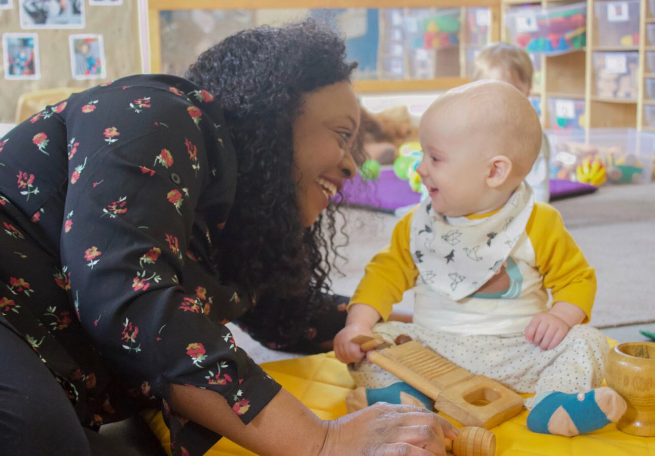 Teacher with a baby holding a musical instrument